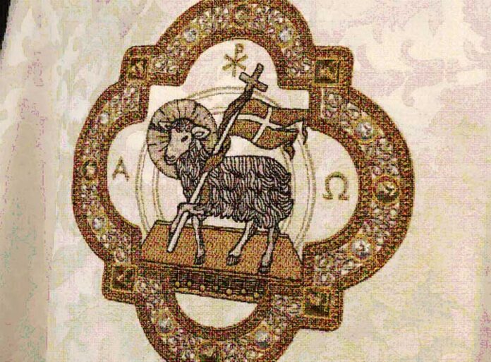 Liturgical chasuble adorned with symbolic Christian embroidery, including a cross a lamb displayed on a mannequin.